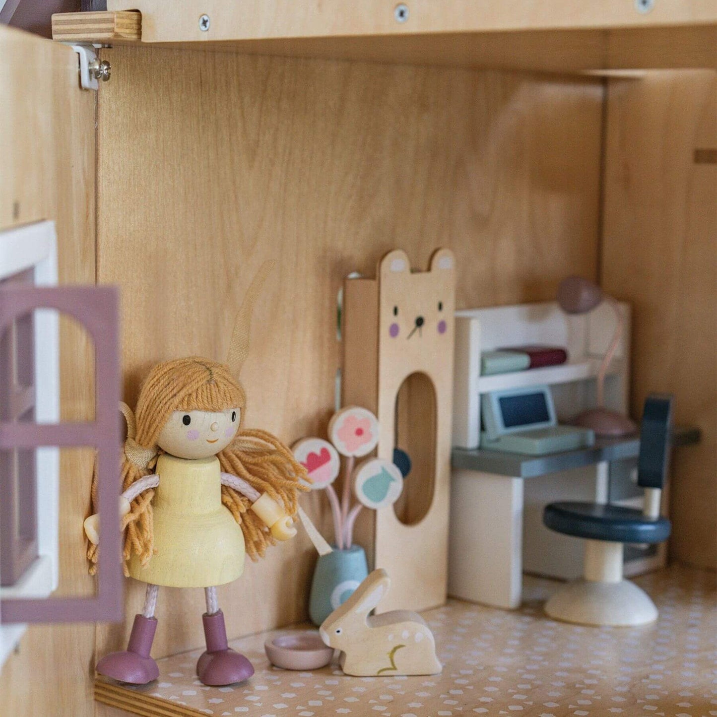 Wooden dollhouse with a doll, rabbit, and furniture inside