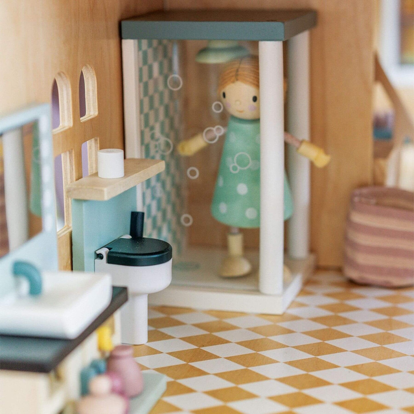 Wooden dollhouse with a doll standing inside, surrounded by furniture and decor.