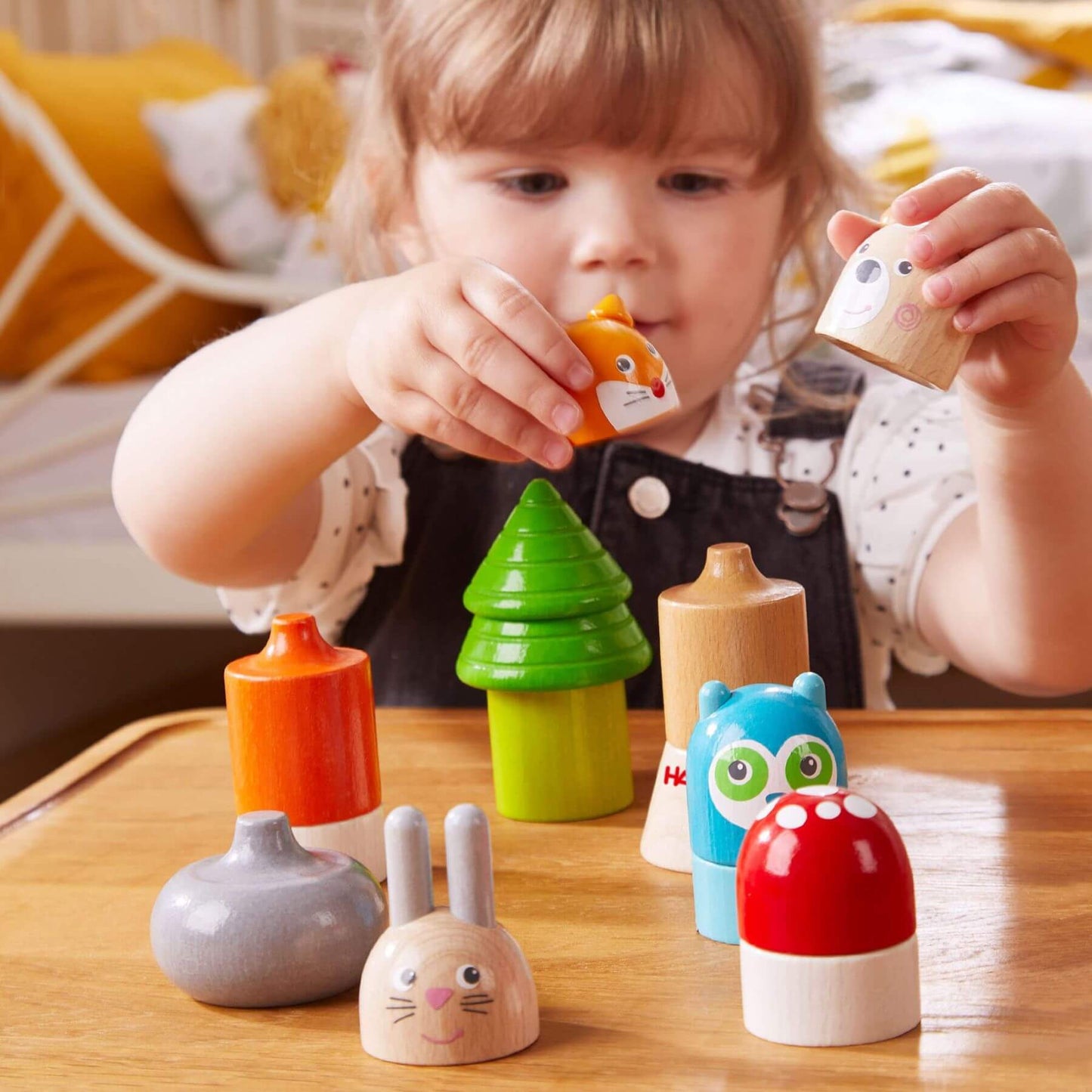 Child playing with HABA USA Forest Animals Wooden Stacking Toy on a table