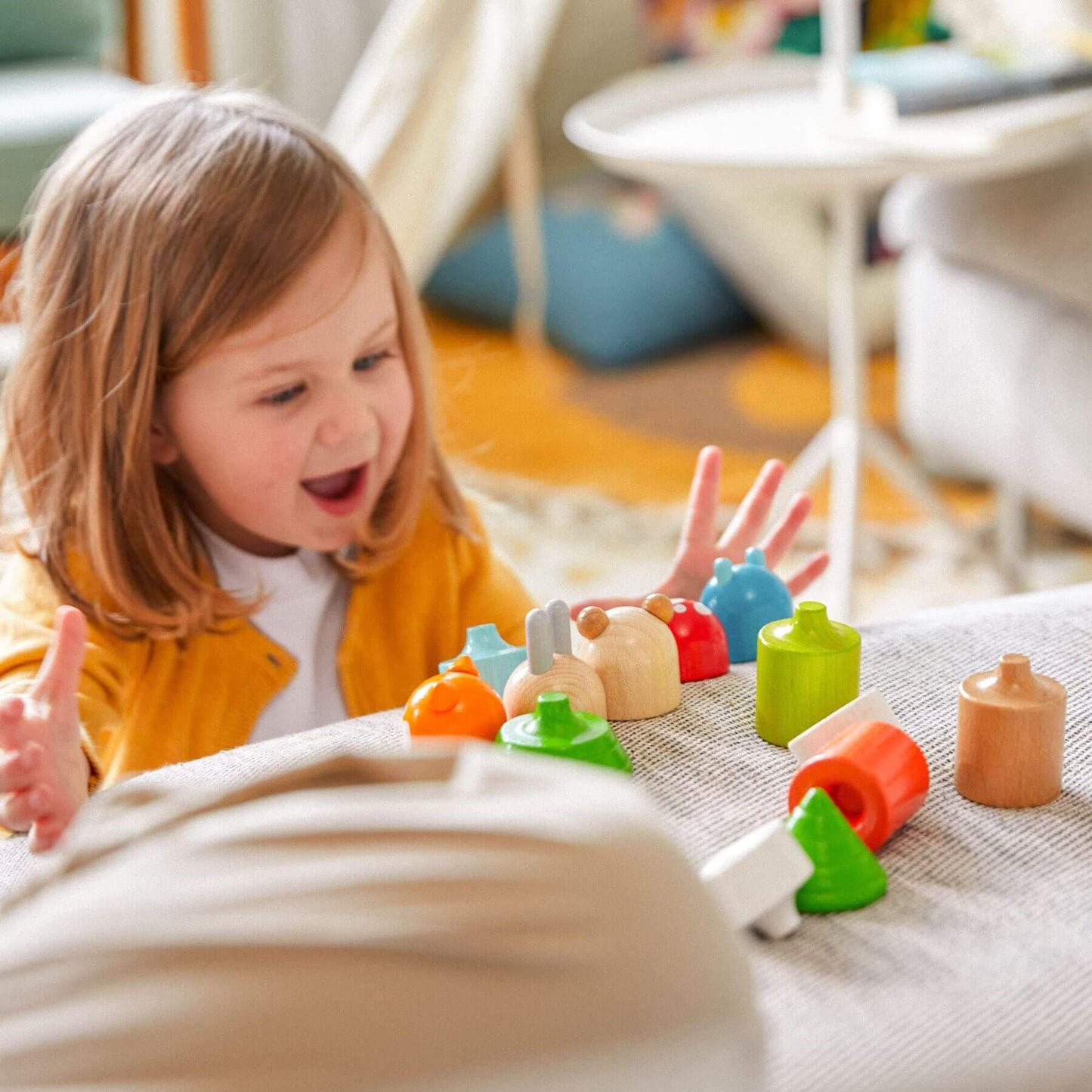 Child playing with HABA USA Forest Animals Wooden Stacking Toy on a blanket