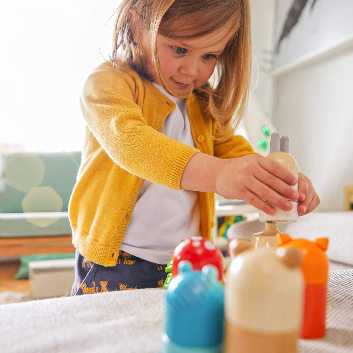 Child playing with HABA USA Forest Animals Wooden Stacking Toy on a bed