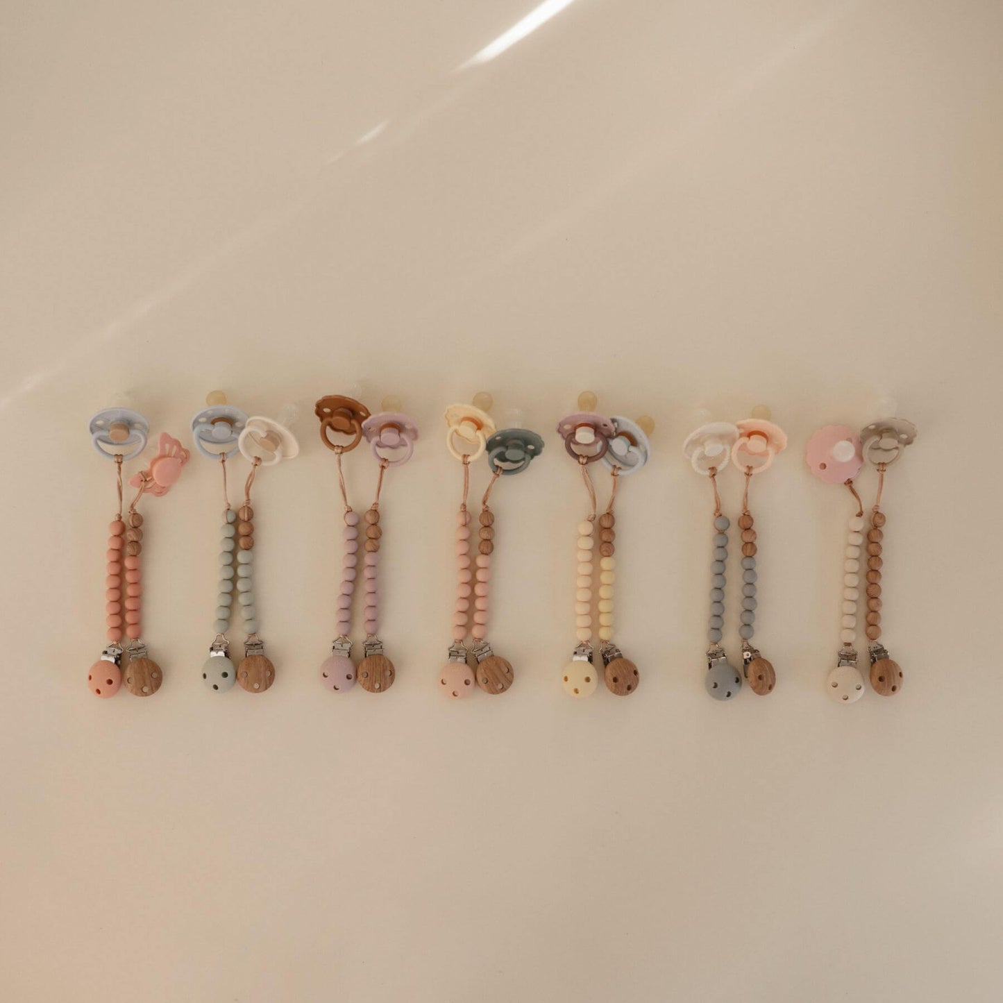 Row of colorful baby teething toys on a beige background