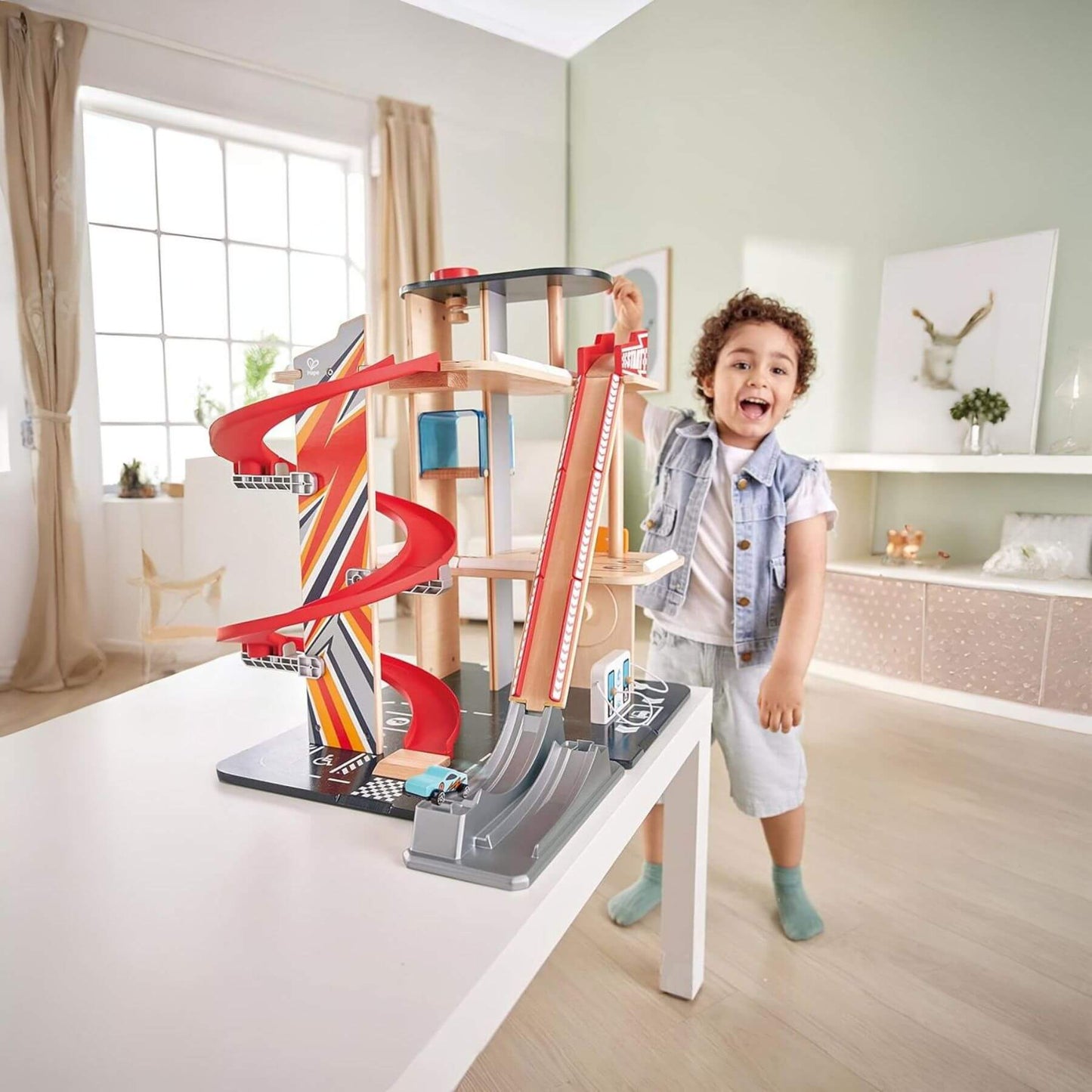 Child playing with Hape Gearhead Stunt Garage in a modern living room