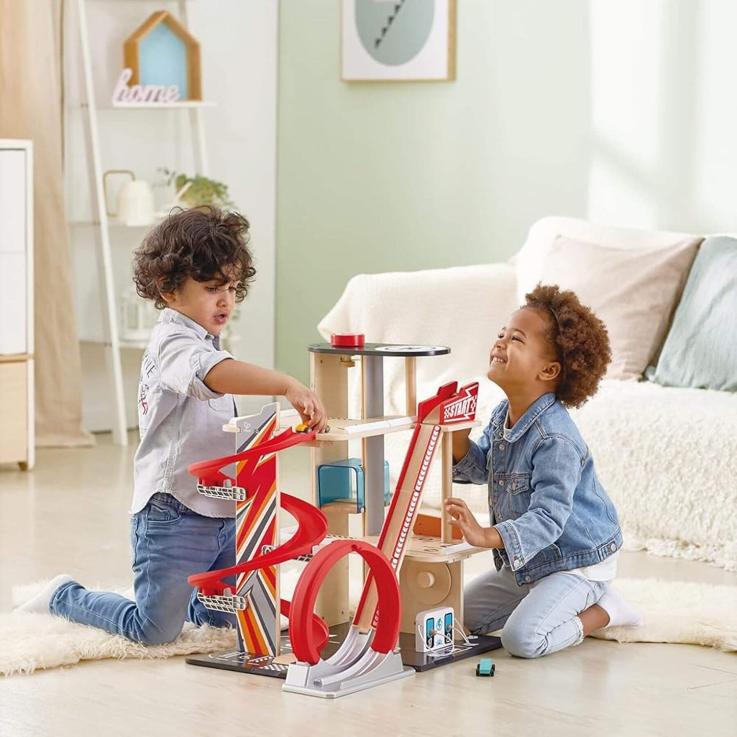 Two children playing with Hape Gearhead Stunt Garage in a living room.