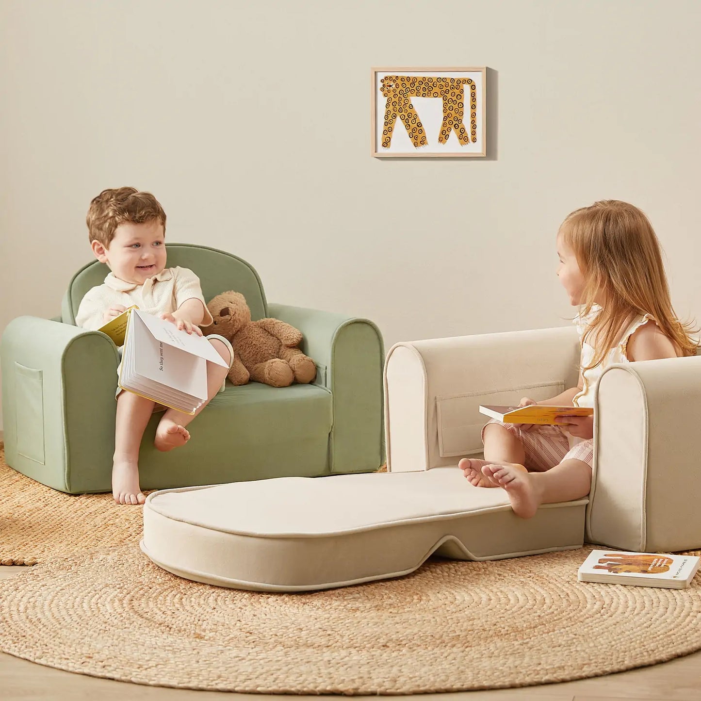 Two children sitting on green and beige Tiny Land® GentleSnug Kid Chair with a small table between them, reading books.