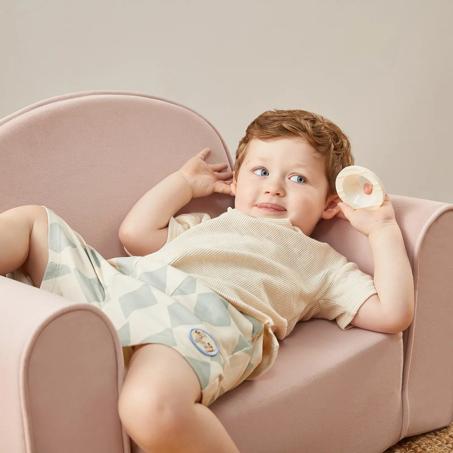 Child lying on Tiny Land® GentleSnug Kid Chair Pink