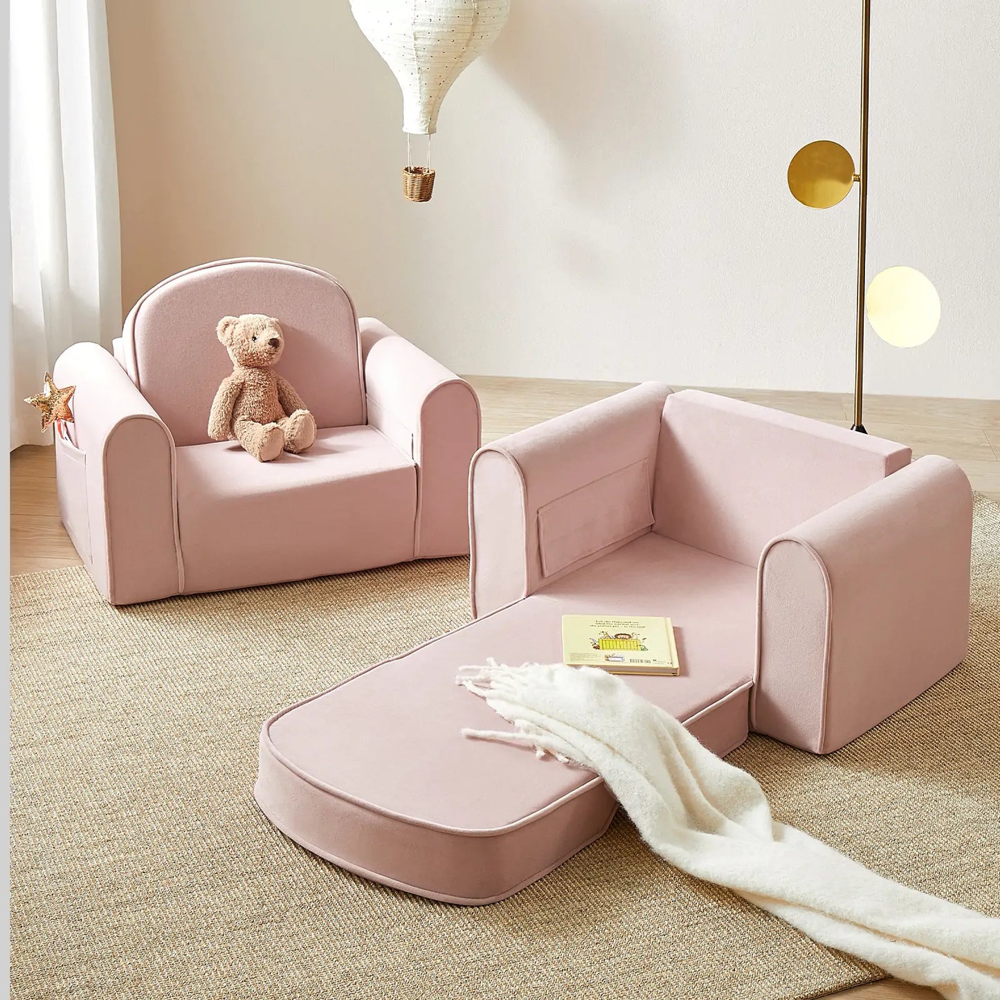 2 Tiny Land® GentleSnug Kid Chair Pink with a teddy bear and blanket in a room.