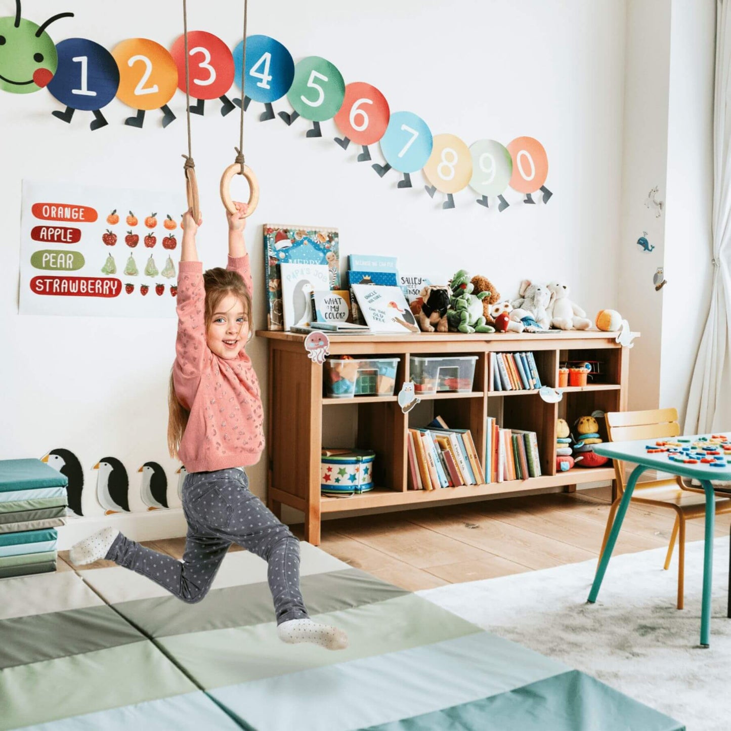 Child playing with a ring on a colorful number wall decal in a playroom.