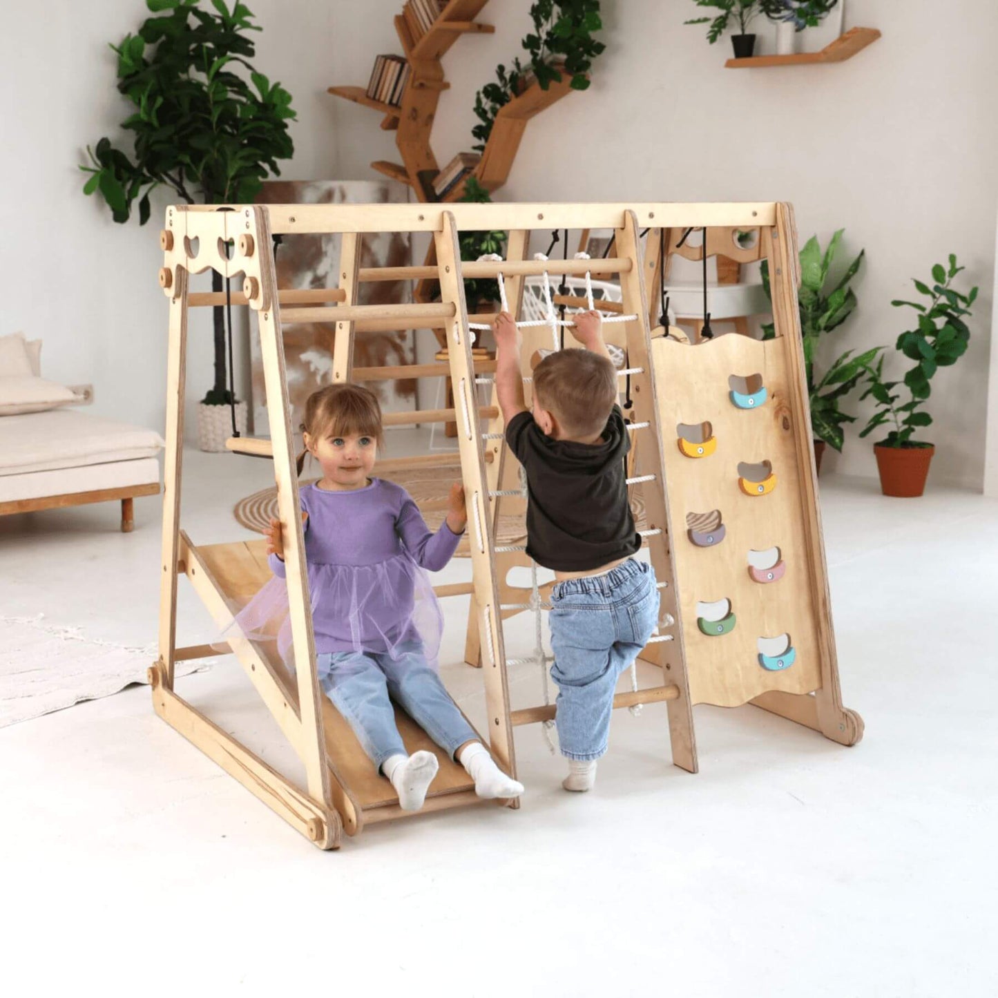 Children playing on Goodevas 6in1 Indoor Jungle Gym in a room with plants and shelves.