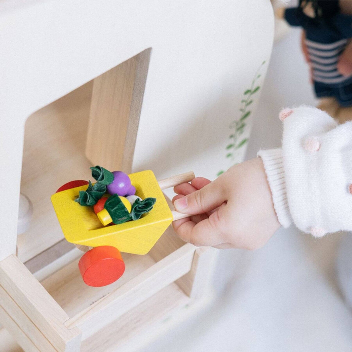 Child's hand interacting with a colorful toy on a wooden shelf
