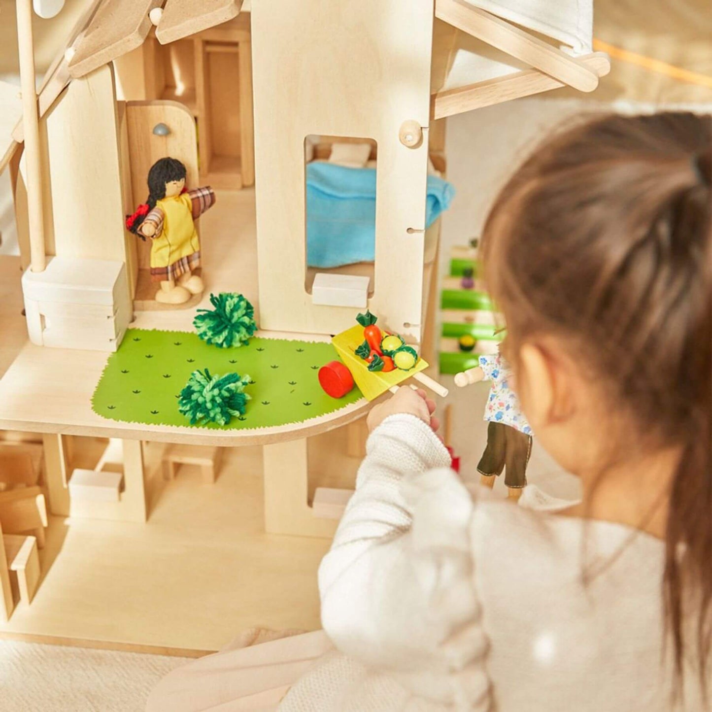 Child playing with PlanToys Green Dollhouse With Furniture indoors