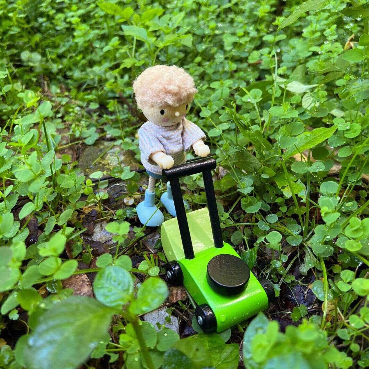 Small toy figure on a green toy car in a grassy area