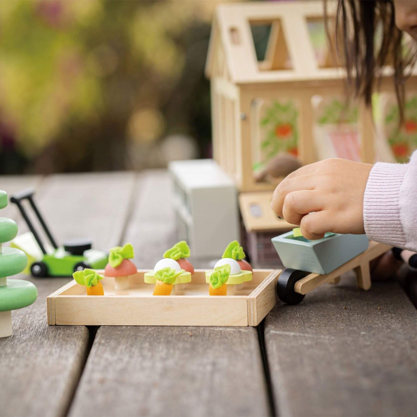 Child playing with wooden toy garden set outdoors