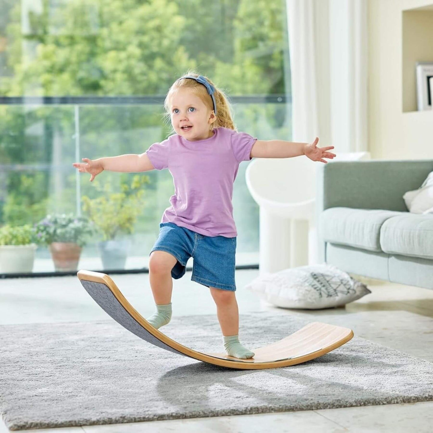 Child balancing on Hape Light Up Balance Board in a living room.