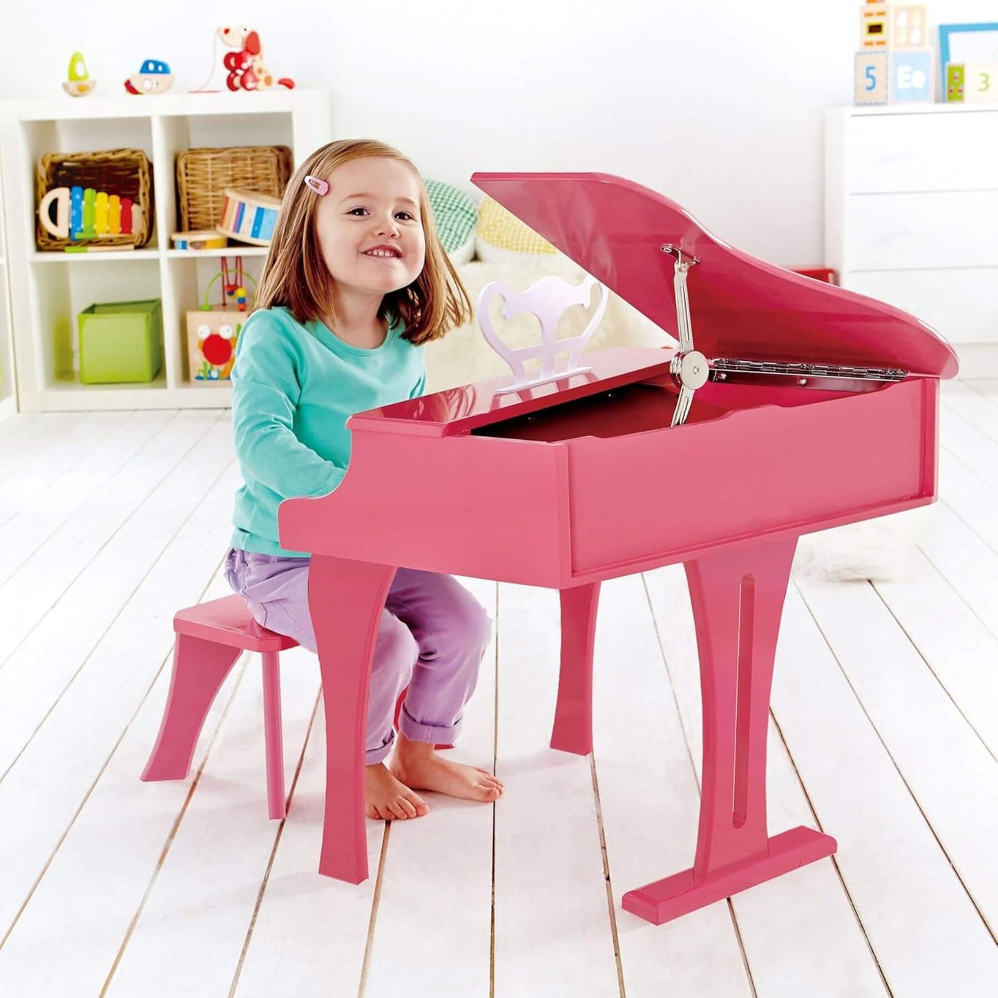Child playing Hape Happy Grand Piano Pink in a bright room