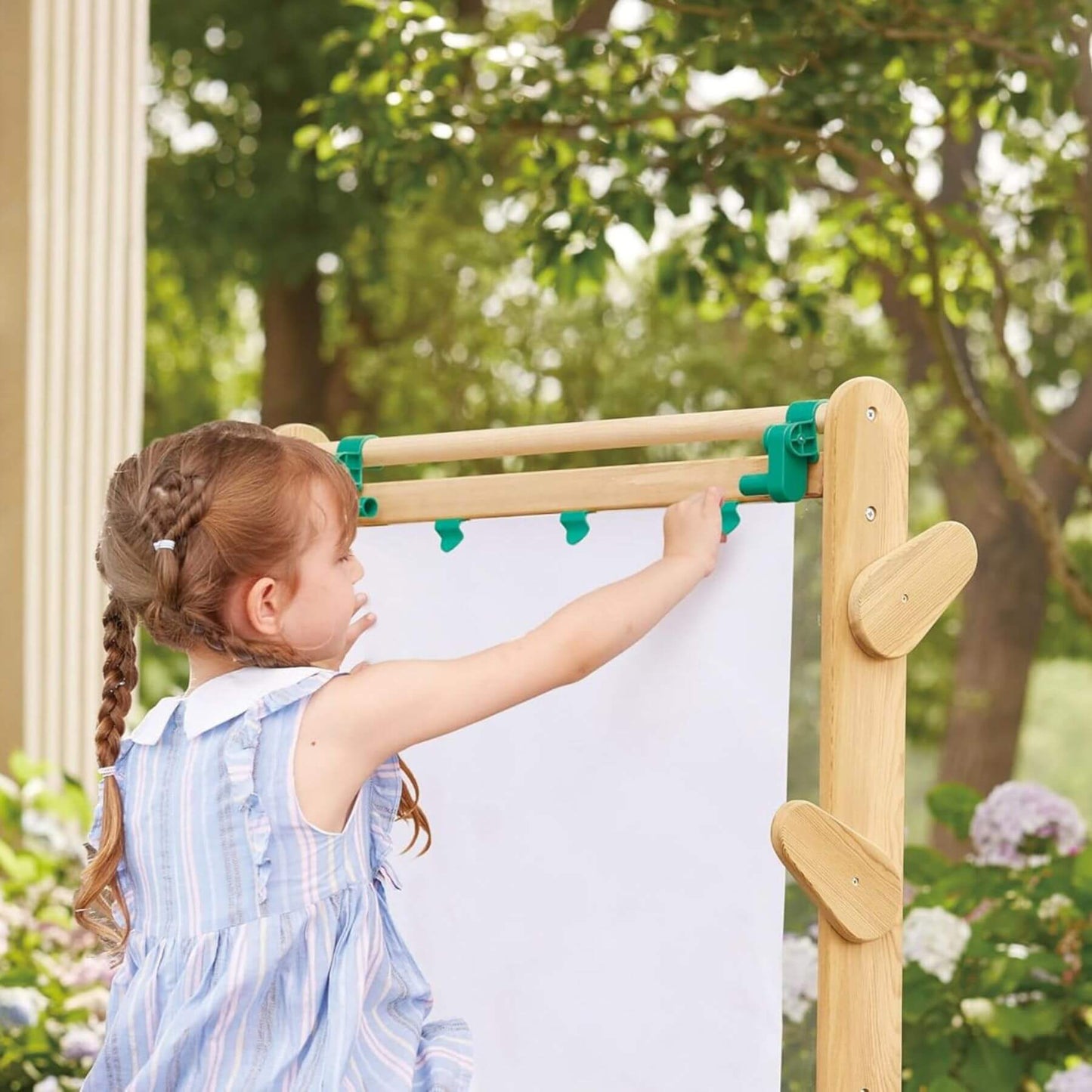 Child using Hape Outdoor Art Easel with green clips outdoors