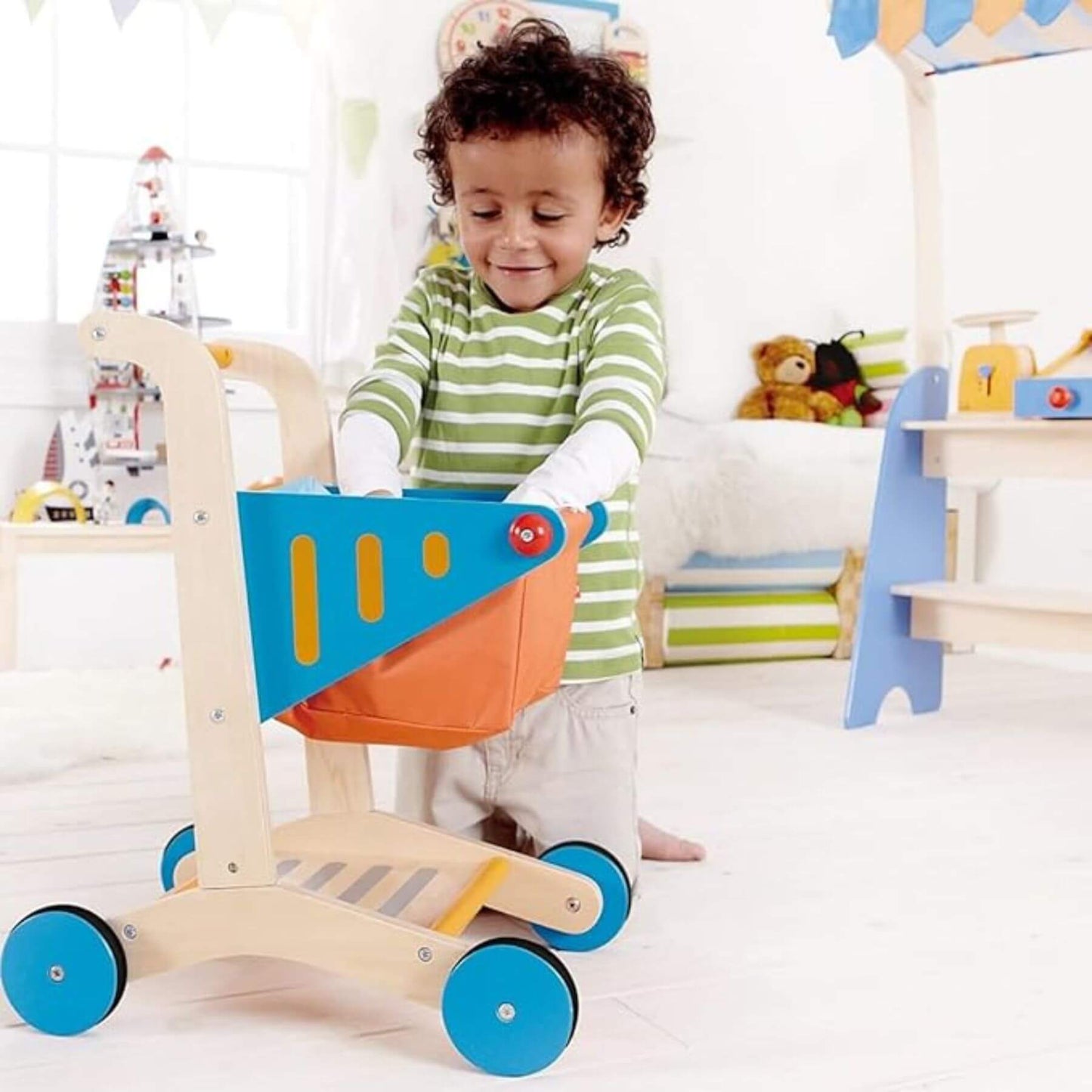 Child playing with Hape Shopping Cart in a playroom.