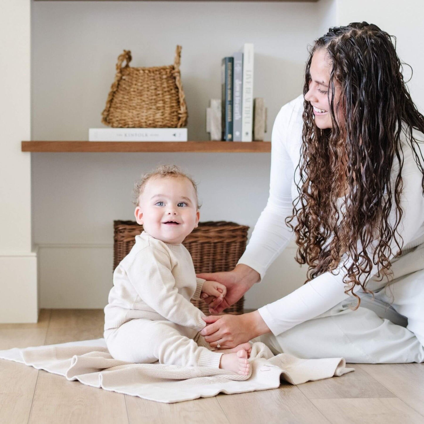 Woman and child sitting on Saranoni Heirloom Cotton Knit Receiving Blanket in a home setting