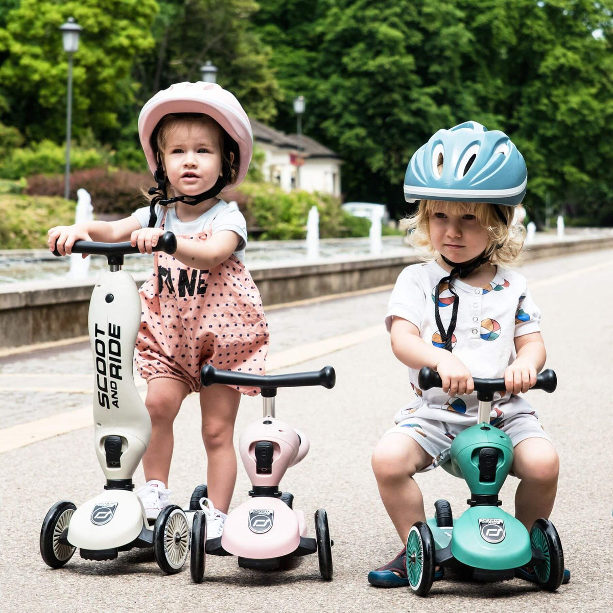 Two children riding scooters in a park setting