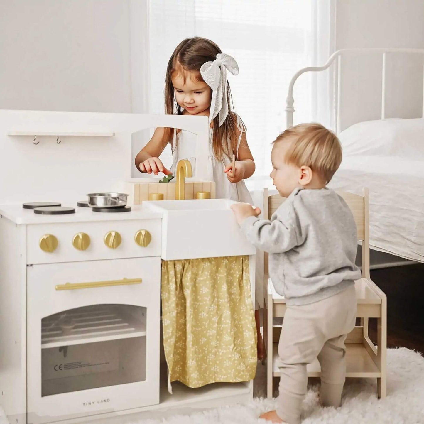 Two children playing with Tiny Land® Honey Kitchenette - Little Chef's First Kitchen in a bright room.