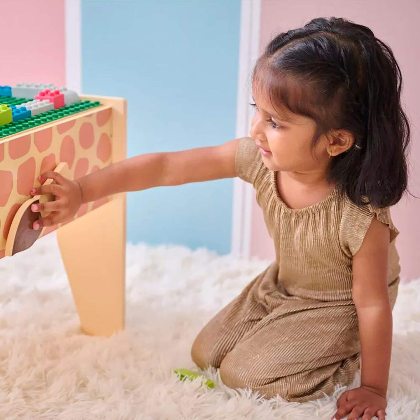 Child playing with Teamson Kids Jungle Giraffe 2-in-1 Wooden Activity Table on a fluffy white rug.