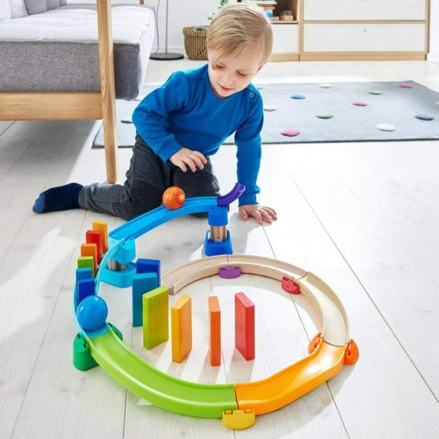 Child playing with HABA USA Kullerbu Kringel Domino Play Track Starter Set on a light wooden floor.