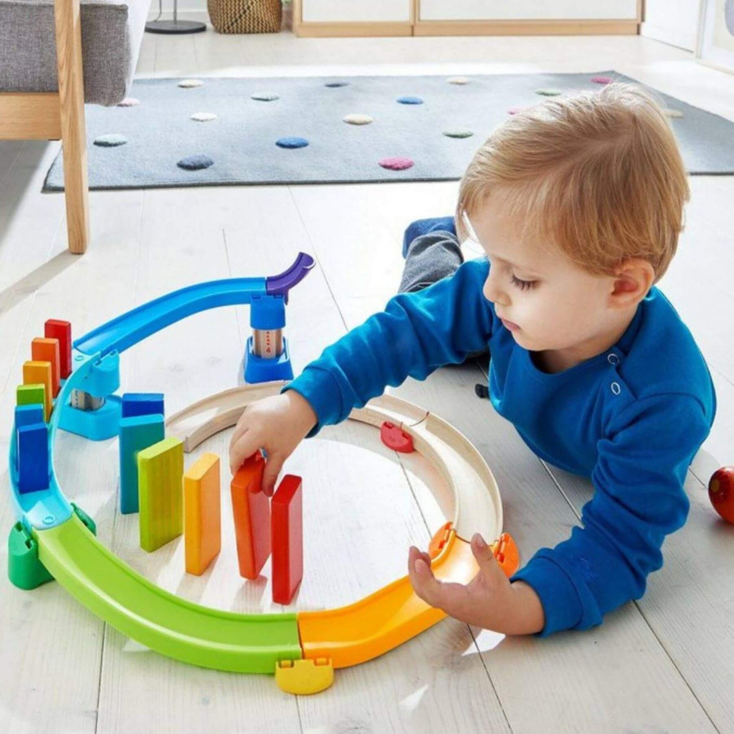 Child playing with HABA USA Kullerbu Kringel Domino Play Track Starter Set on a wooden floor.