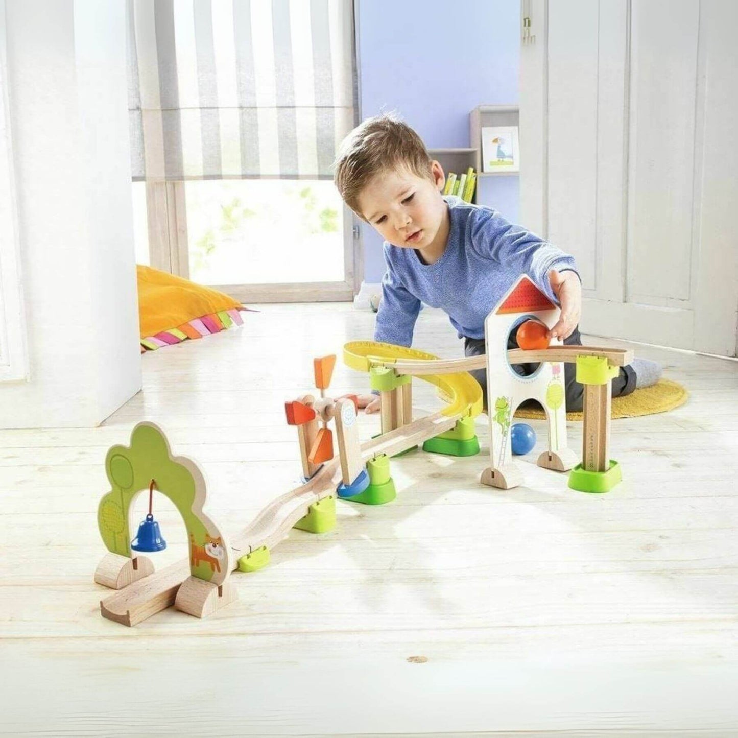 Child playing with HABA USA Kullerbu Windmill 25 Piece Starter Track Set in a bright room.