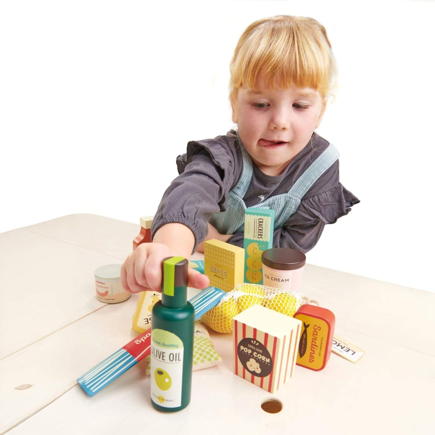 Child playing with toy kitchen items on a white surface