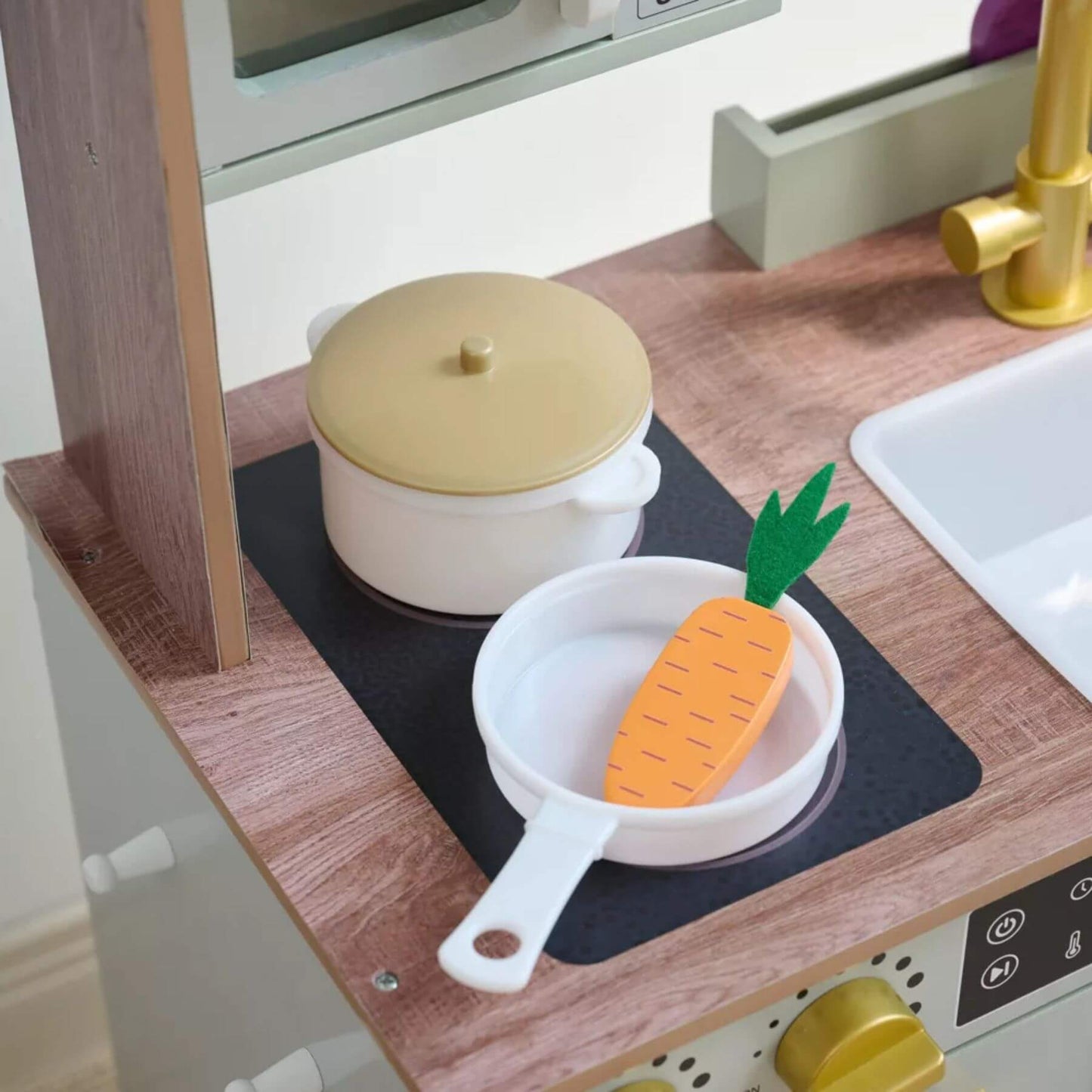 Children's play kitchen set with toy pots and pans on a wooden surface.