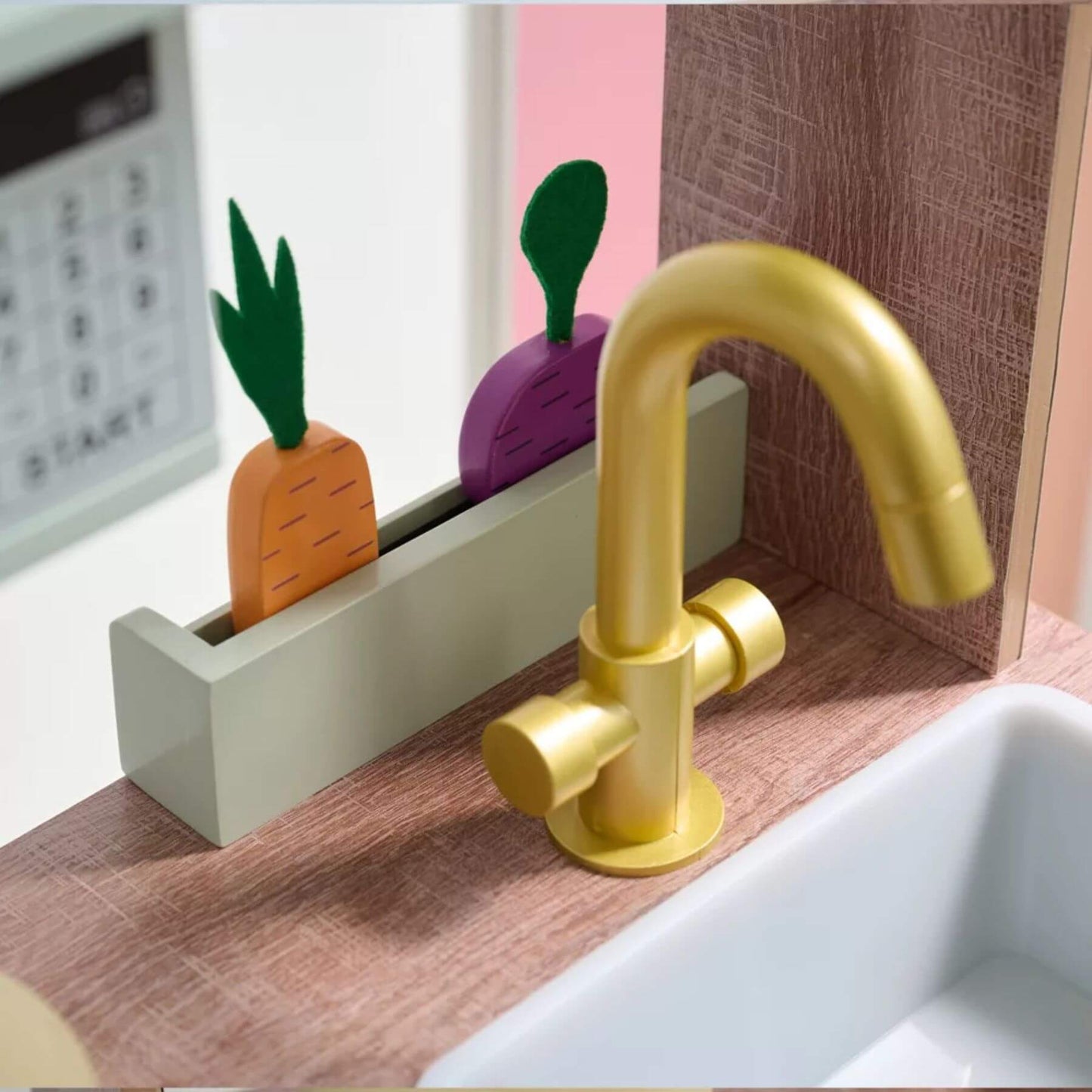 Gold faucet on a wooden surface with colorful soap dispenser in the background