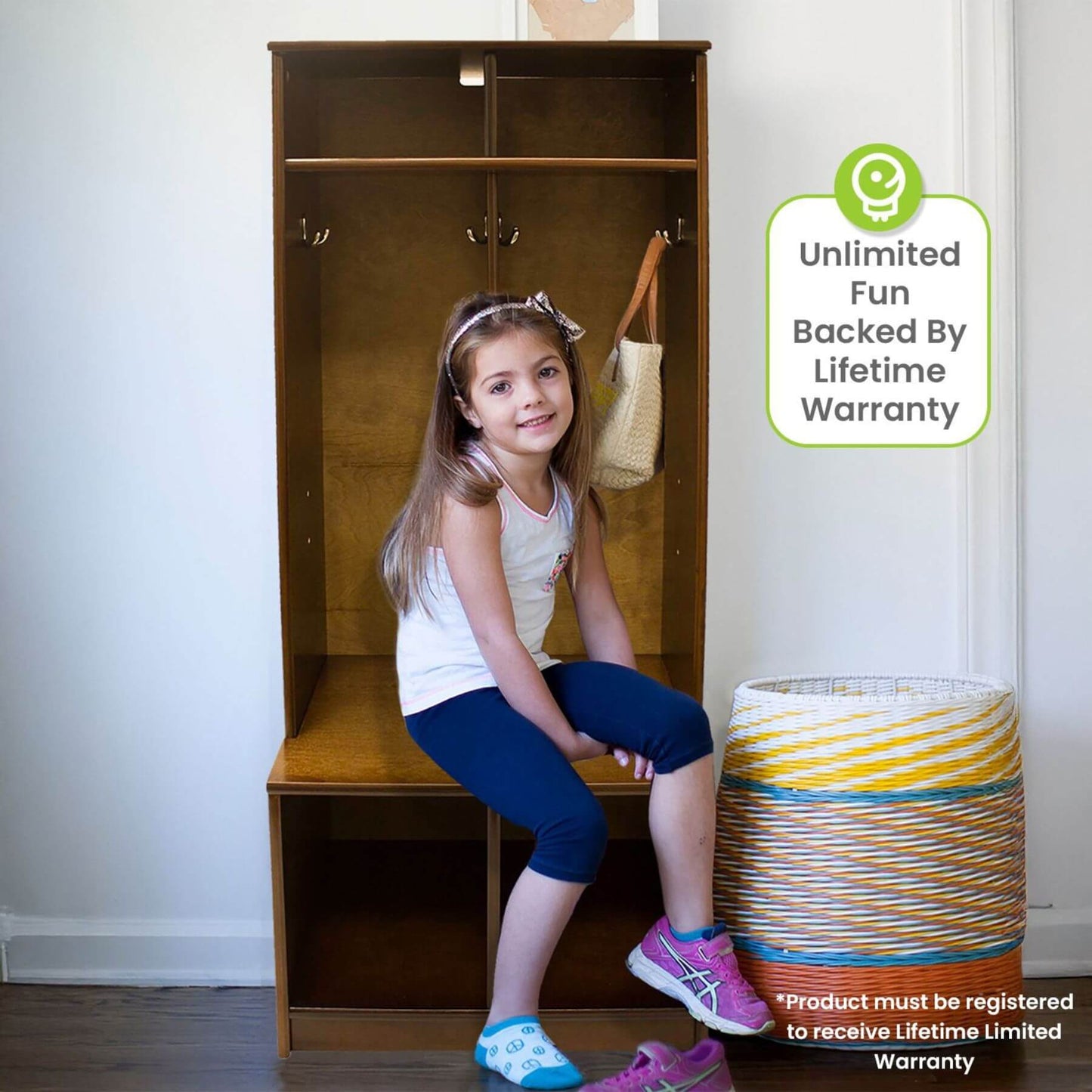 Young girl sitting on Little Partners Learn 'N Store Cubby with a product warranty label in the corner.
