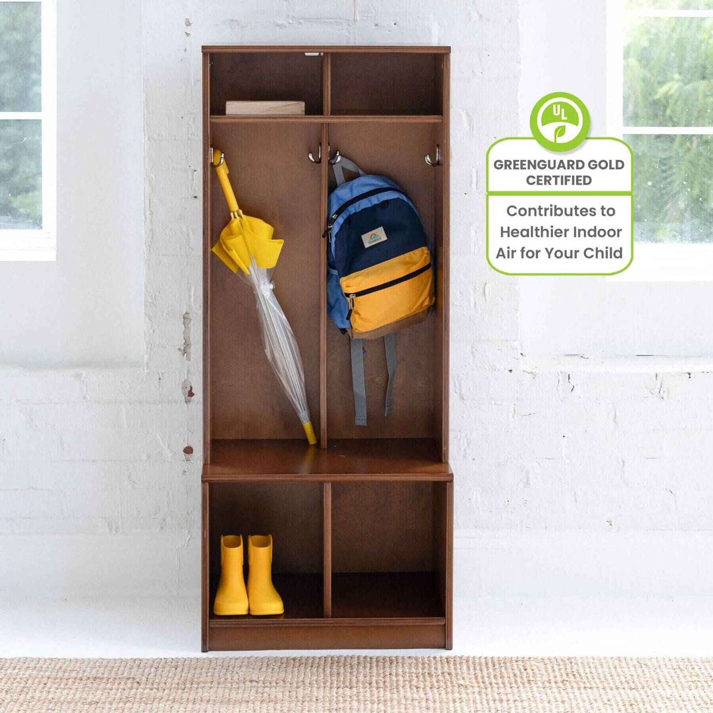 Little Partners Learn 'N Store Cubby with backpack, umbrella, and boots against a white brick wall.