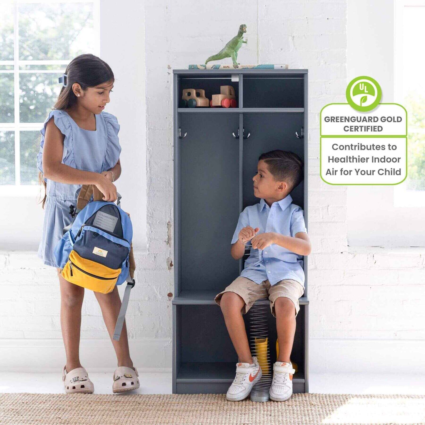 Two children interacting with Little Partners Learn 'N Store Cubby Grey in a room with a white brick wall.