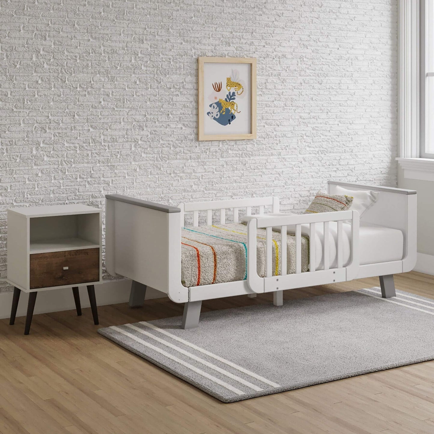 Children's room with a Little Partners MOD Toddler Bed Grey & White, nightstand, and framed artwork on a brick-patterned wall.