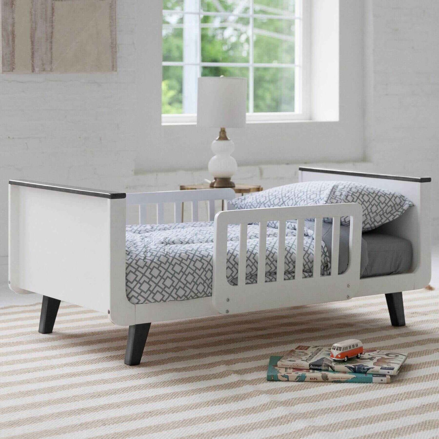 Little Partners MOD Toddler Bed Grey & White with gray bedding in a room with a window and toys on the floor.