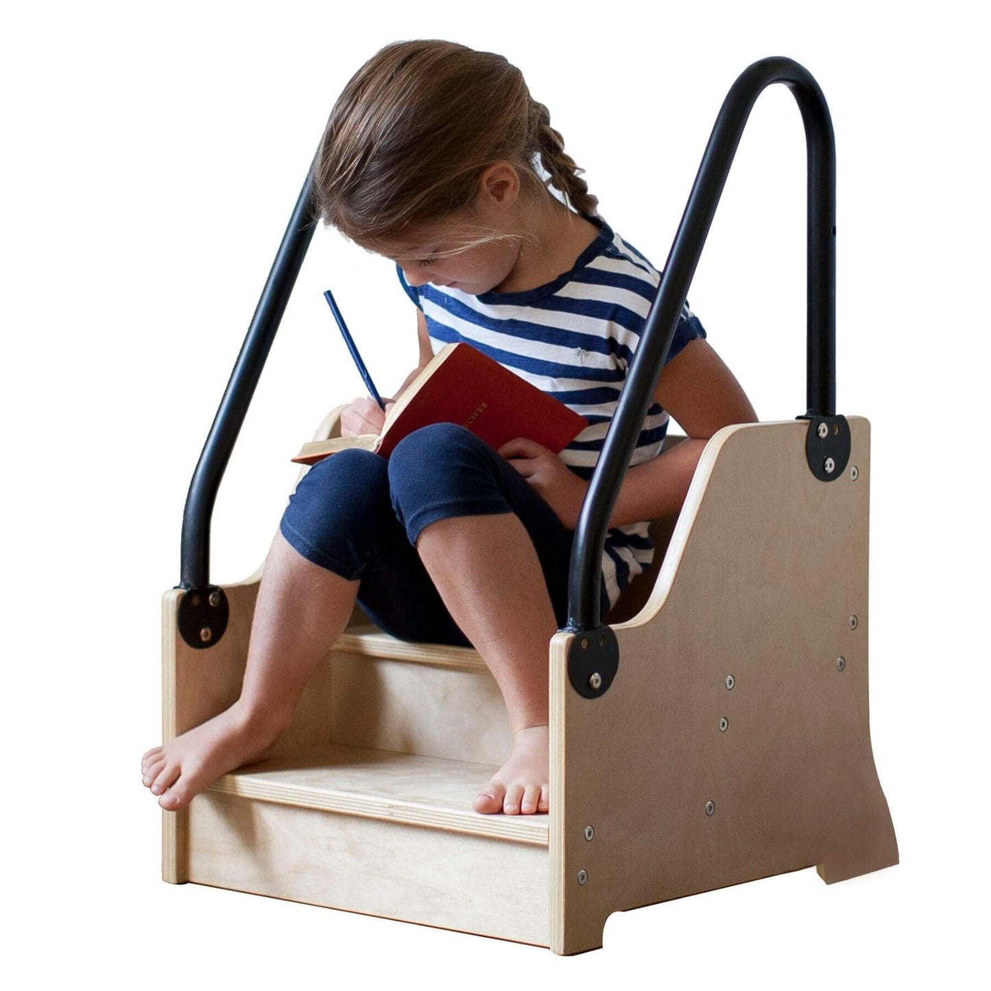 Child sitting on a Little Partners ReachUp Step Stool, drawing in a red book.