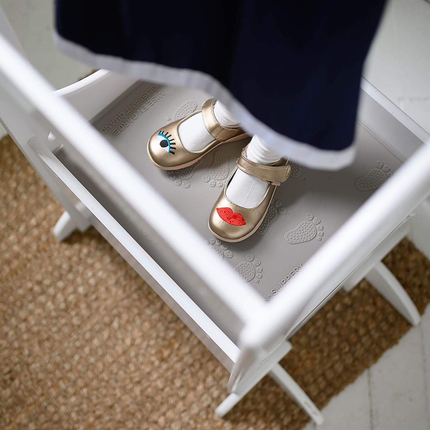 Children's shoes with colorful designs on a white stool.