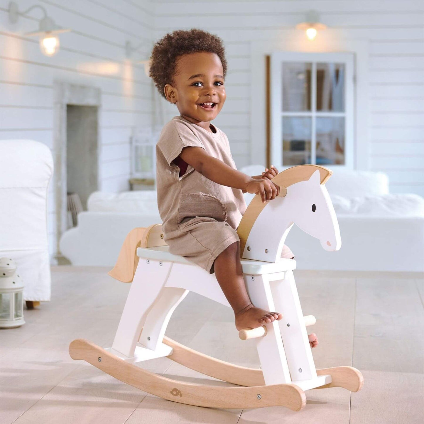 Child sitting onTender Leaf Lucky Rocking Horse in a bright room