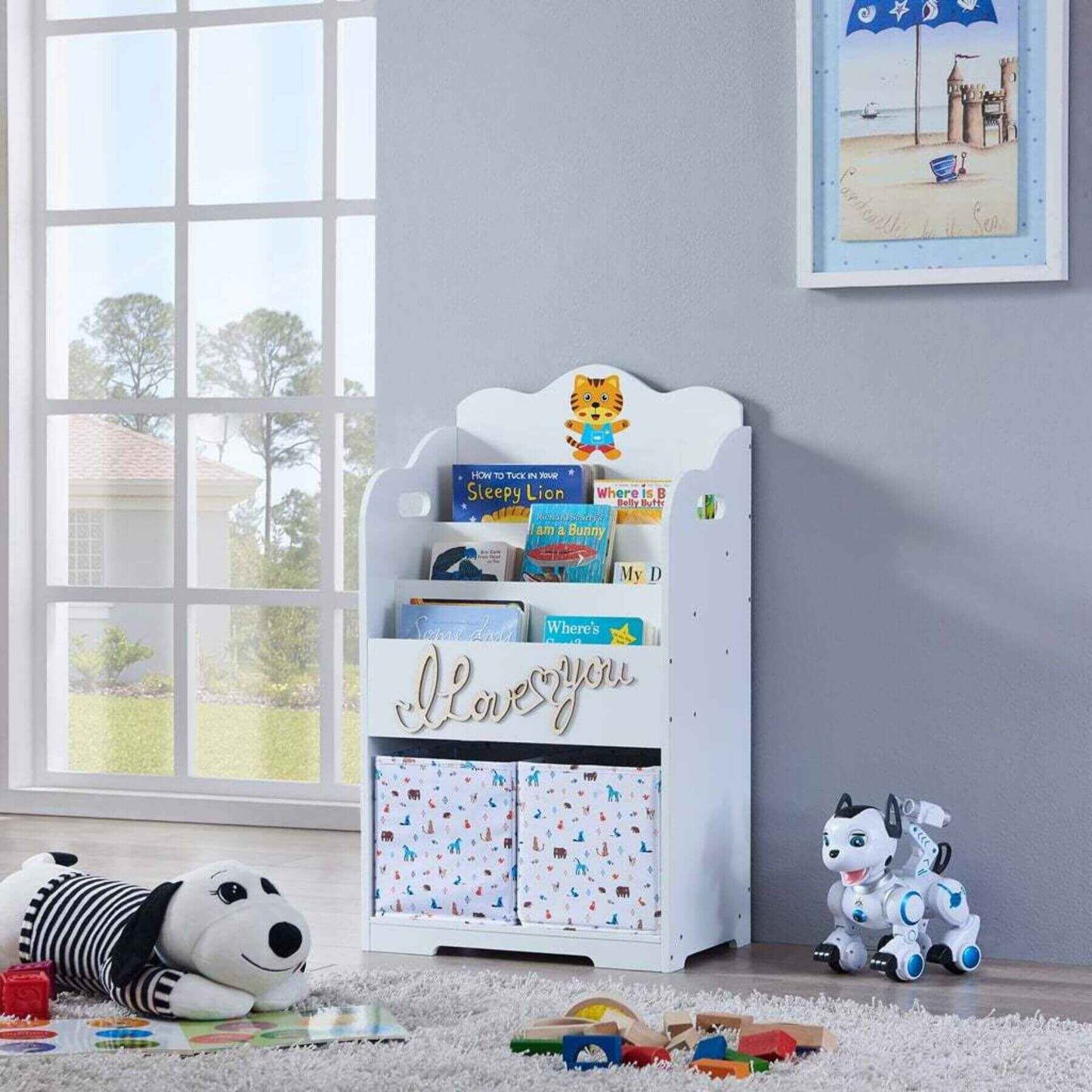 Maison Kids Bookcase with Toy Storage with books and toys in a room with a window and framed picture on the wall.