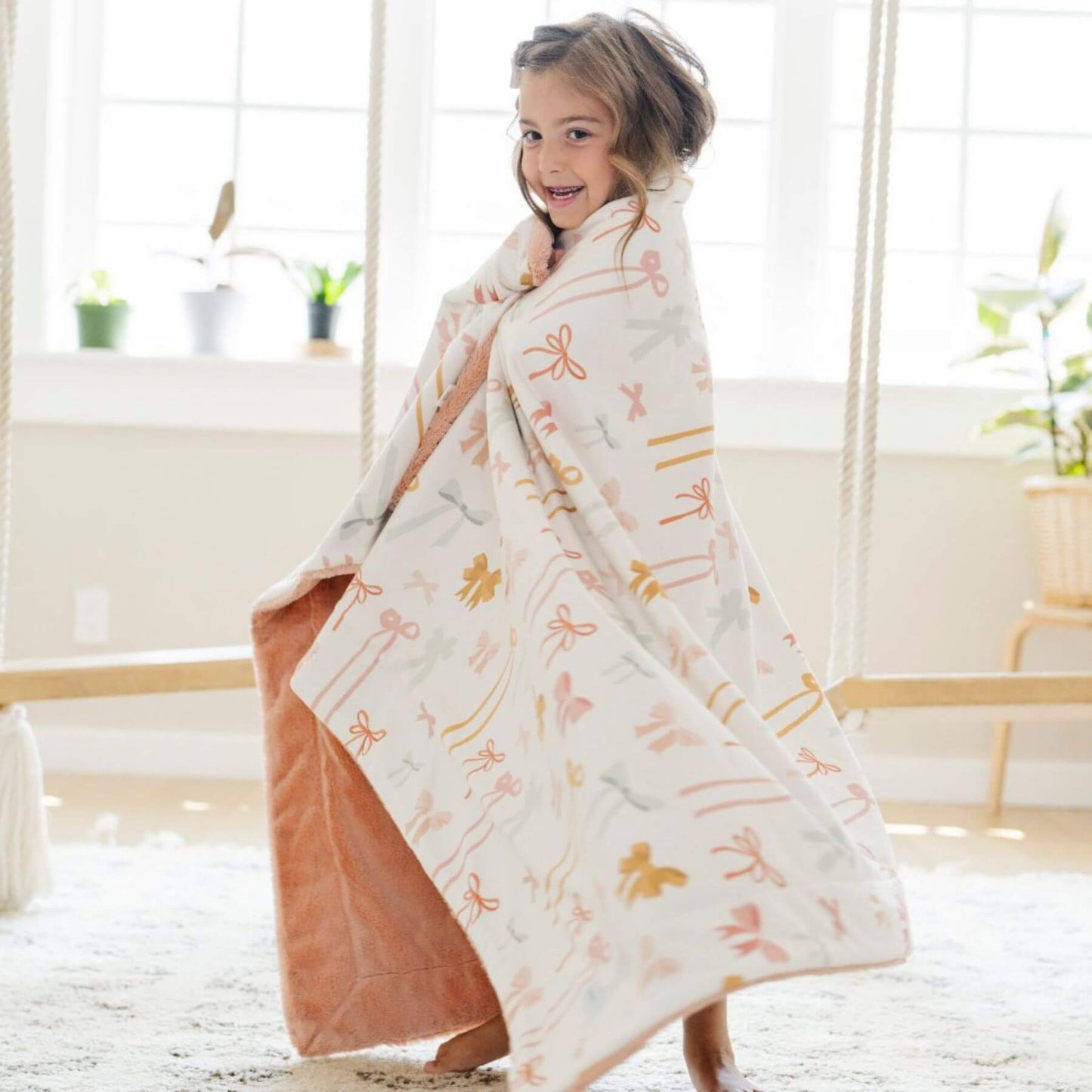 Child wrapped in Saranoni Minky/Lush Toddler Blanket in a bright, minimalistic room.
