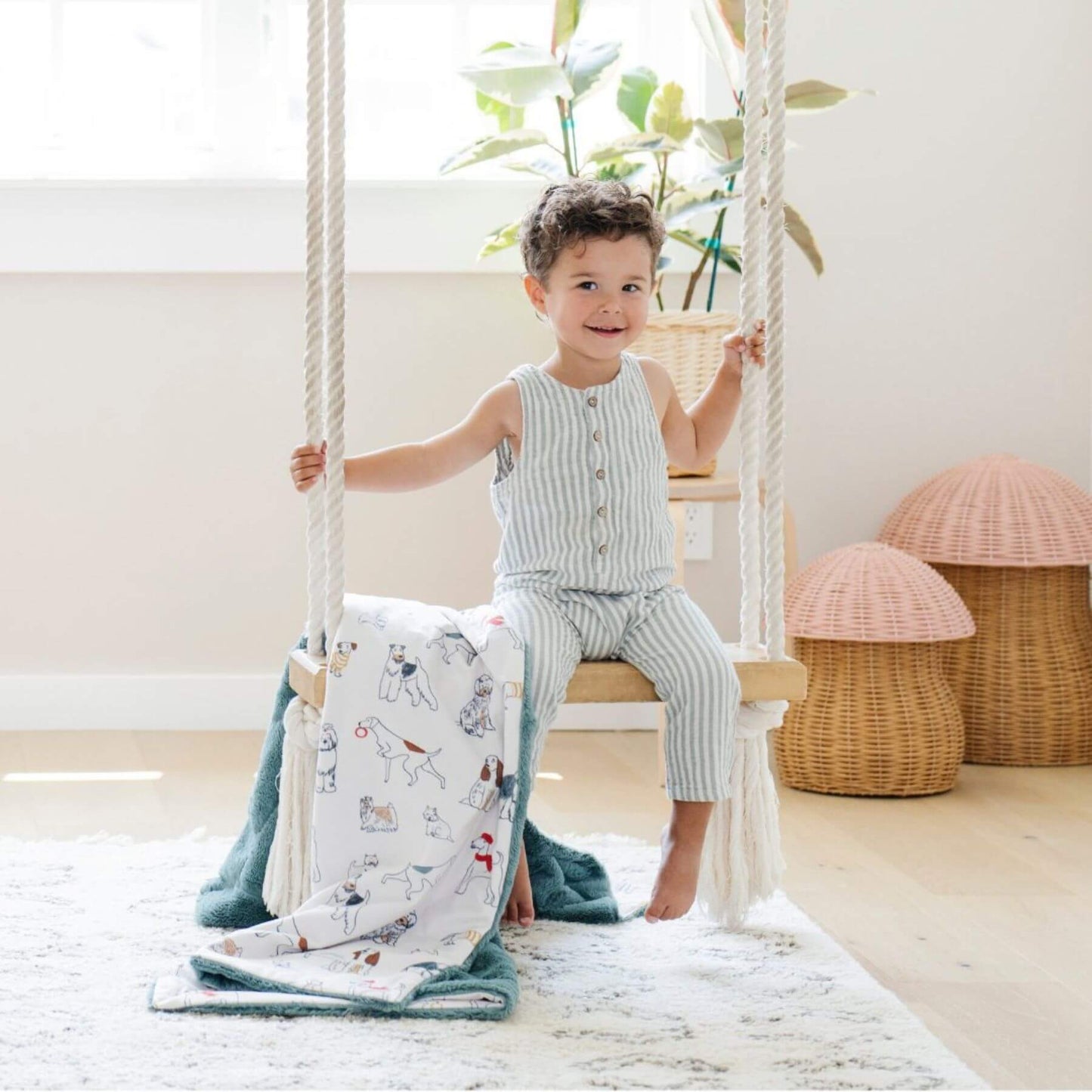 Child sitting on a swing in a room with Saranoni Minky/Lush Toddler Blanket