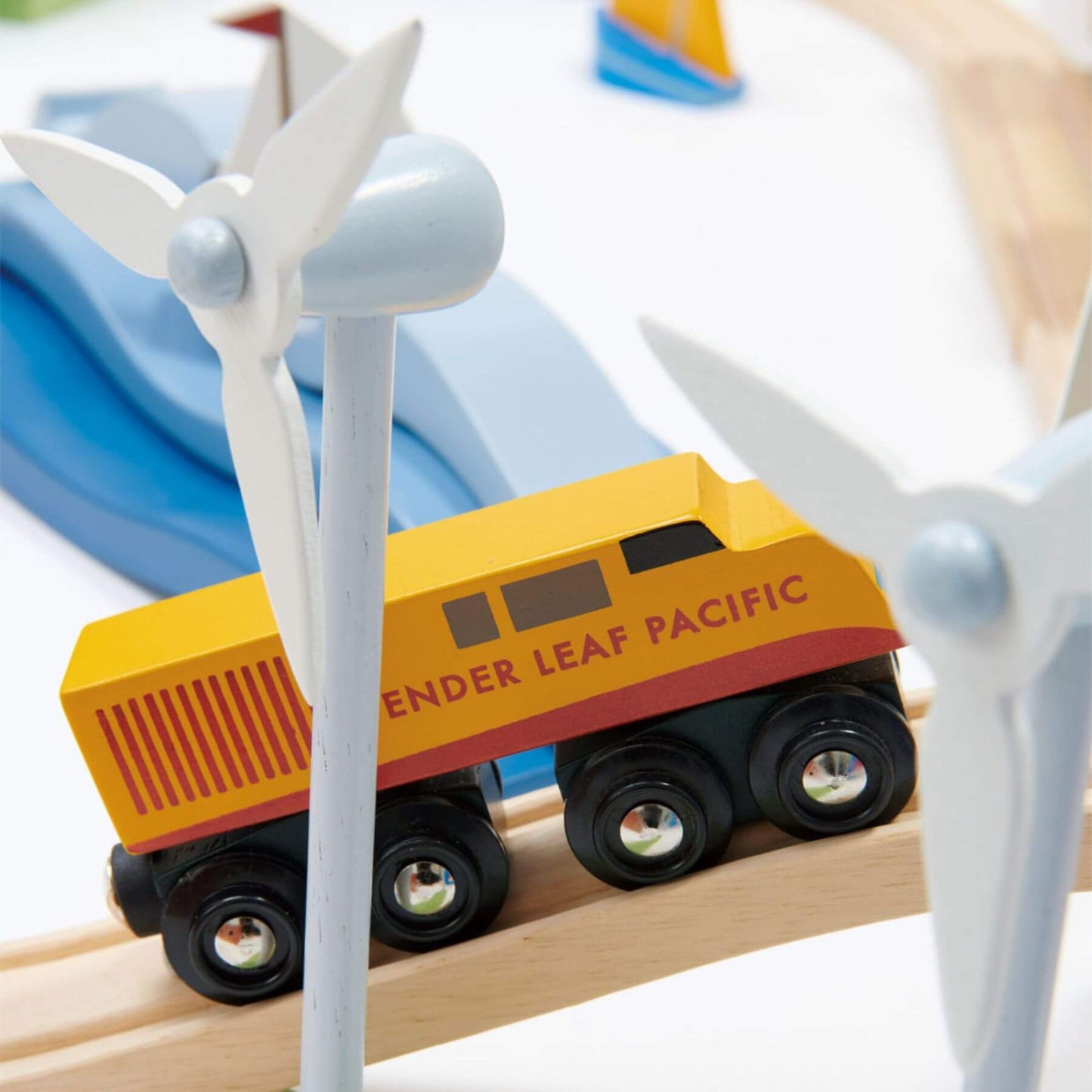 Toy train car on a wooden track with wind turbines in the background