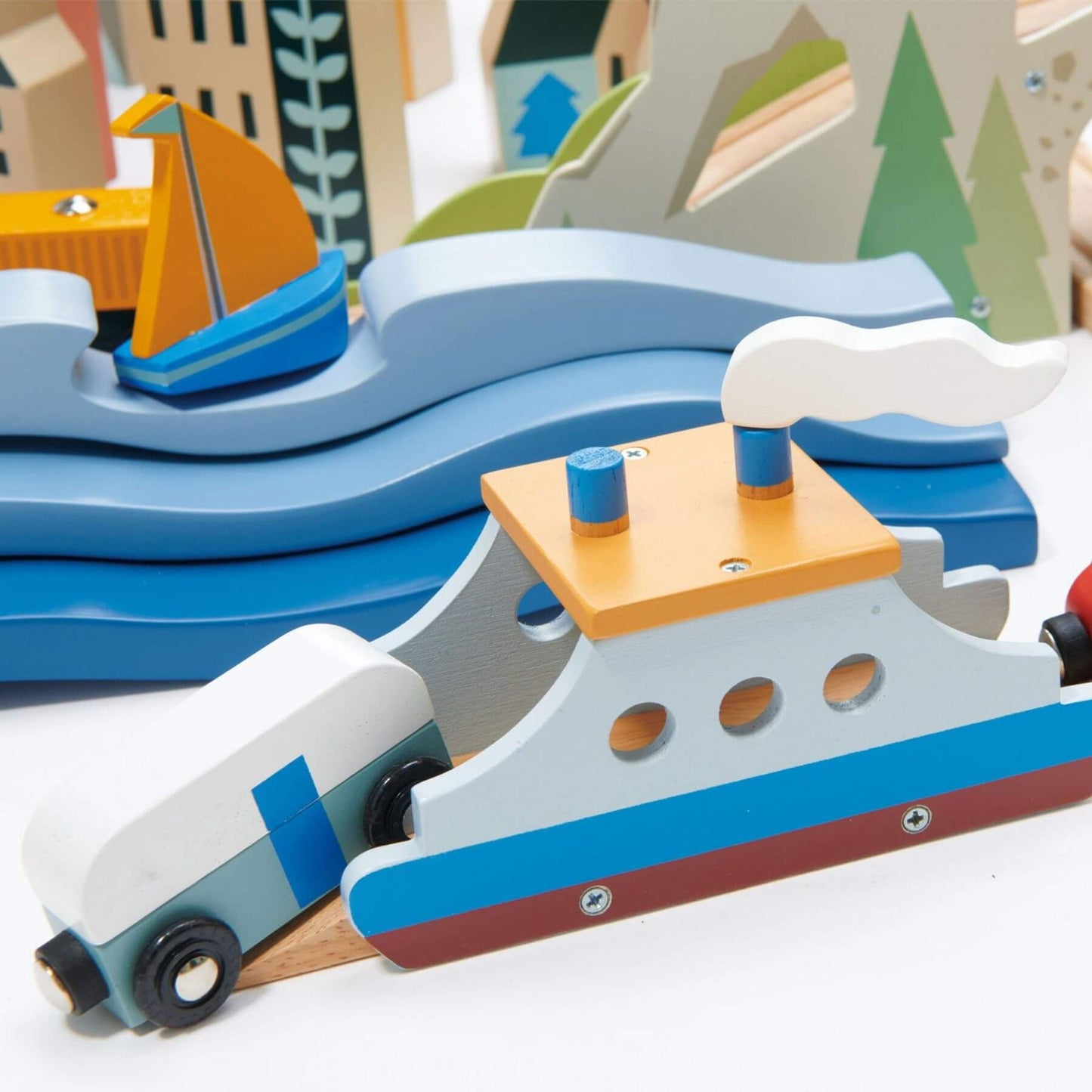 Wooden toy boats on a white surface with a scenic background