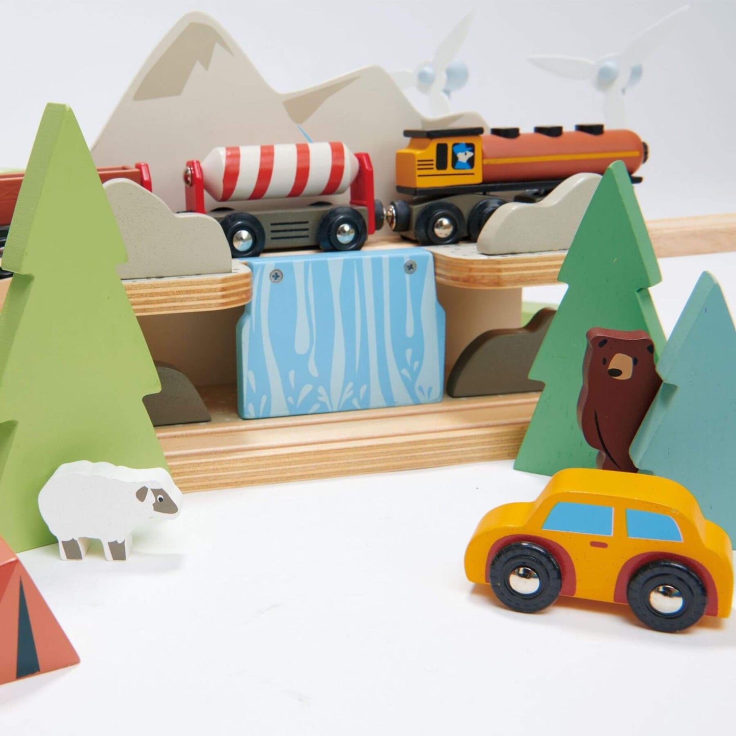 Wooden toy train set with trees, animals, and a car on a white background
