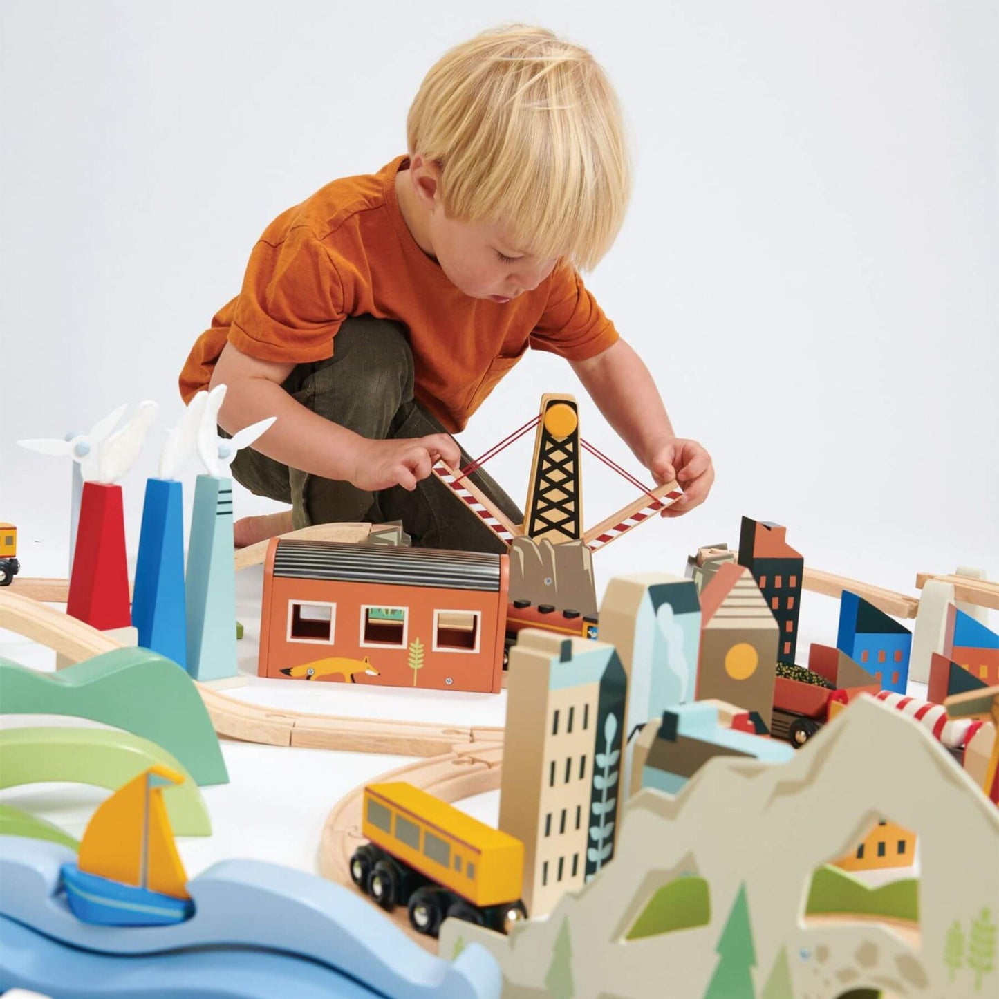 Child playing with Tender Leaf Mountain View Train Set on a white background
