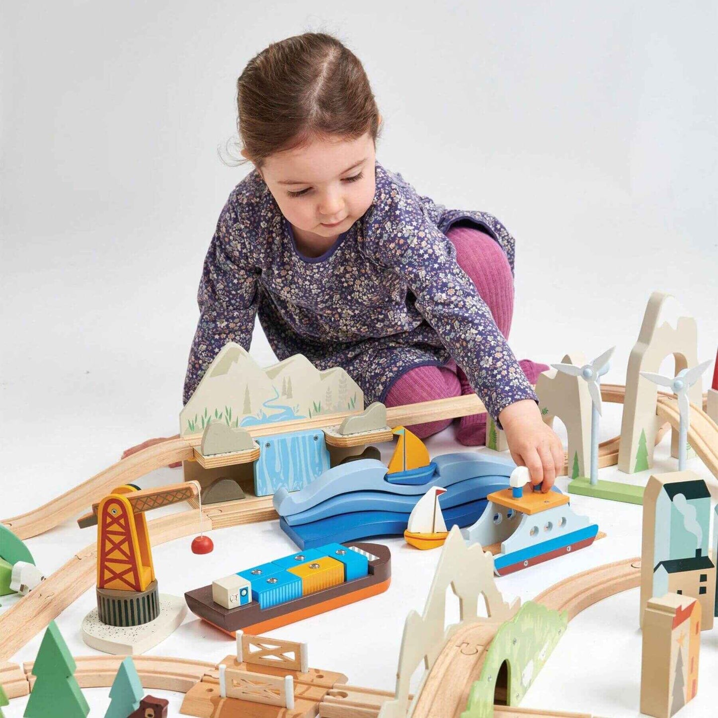 Child playing with Tender Leaf Mountain View Train Set on a white background