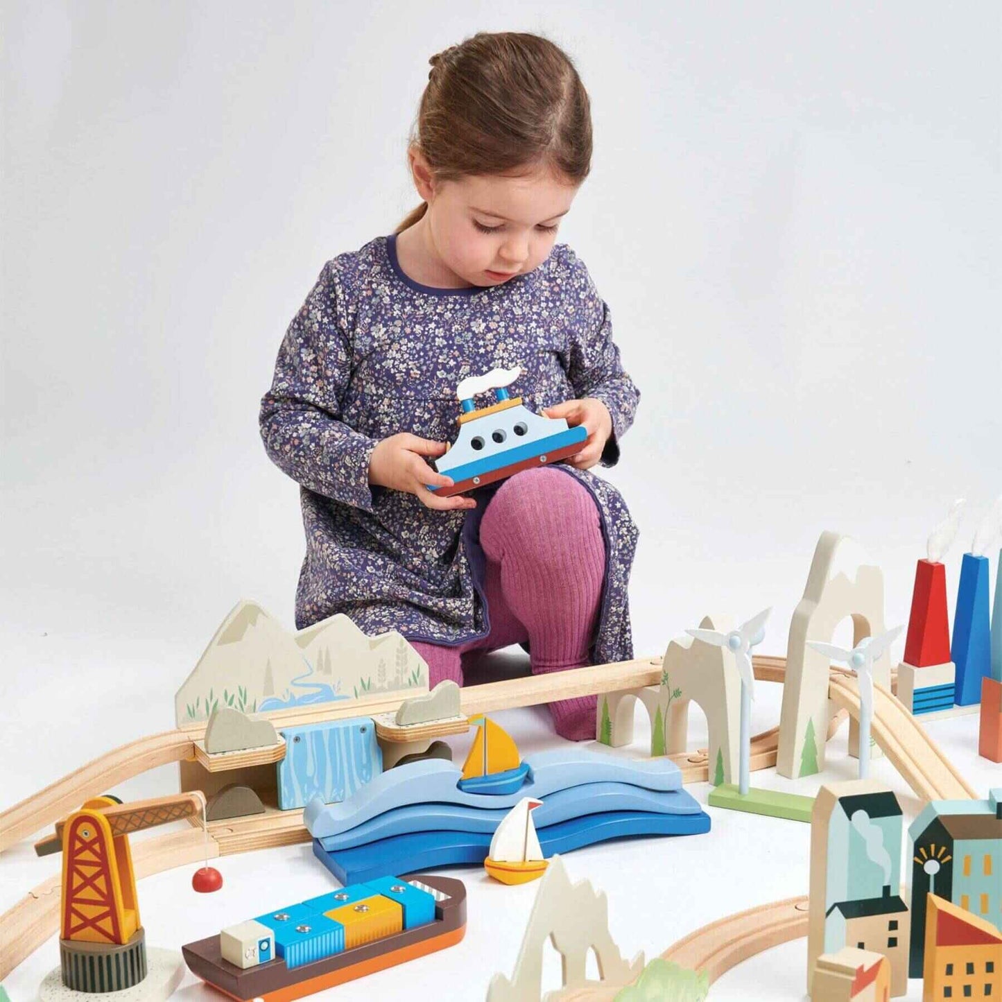 Child playing with Tender Leaf Mountain View Train Set on a white background