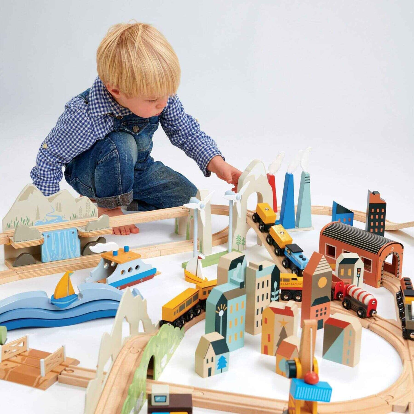 Child playing with Tender Leaf Mountain View Train Set on a white surface