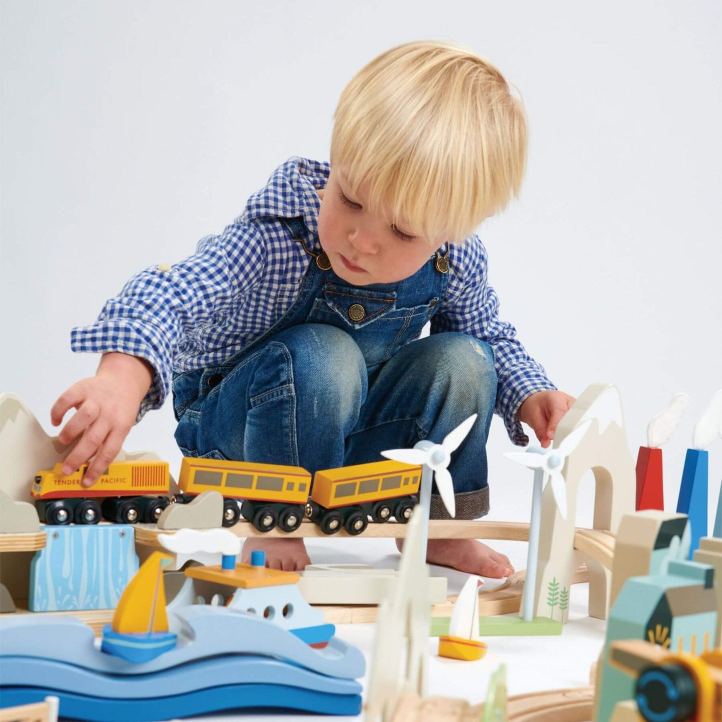 Child playing with Tender Leaf Mountain View Train Set on a white background